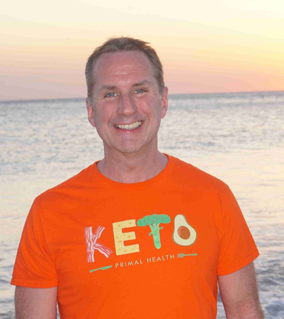 Image of Scott Webb in front of a Florida sunset, wearing his orange Keto Primal Health T-shirt 